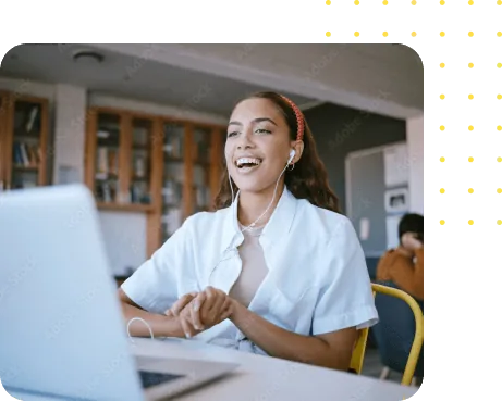 Smiling woman wearing earbuds, engaging in a video call at a desk with a laptop.